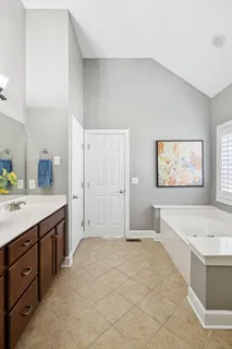 a spacious bathroom with a granite countertop sink a mirror a bathtub and shower