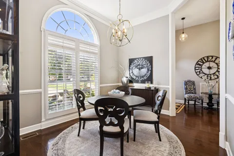 a dining room with furniture wooden floor a rug and a chandelier