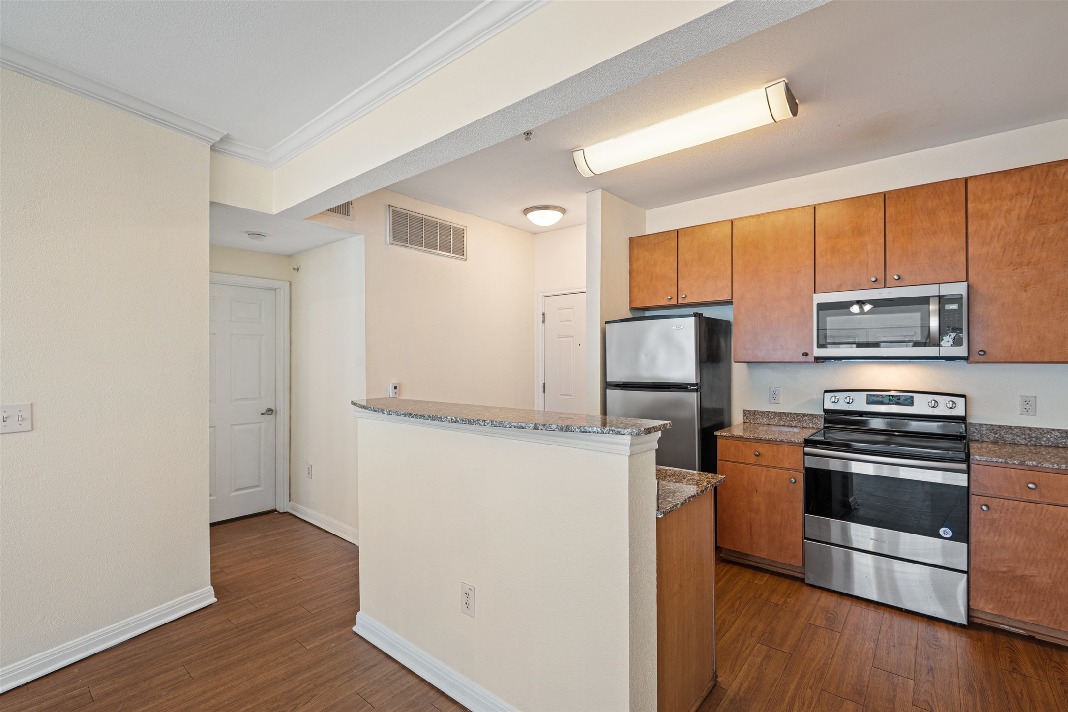 2502 Leon Street, Unit 417 Austin, TX 78705 - Photo 7 of 26 a kitchen with wooden cabinets and stainless steel appliances