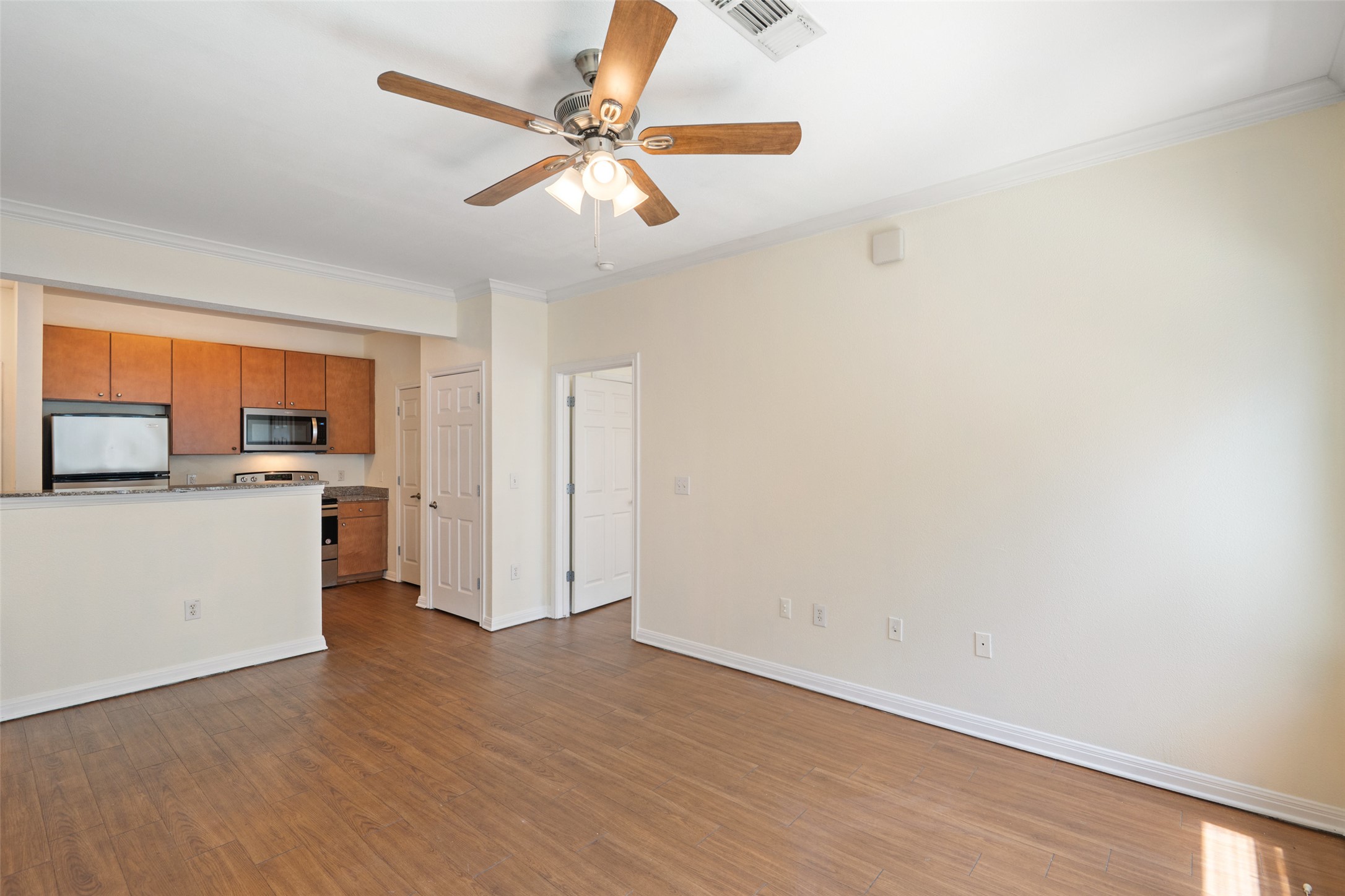 2502 Leon Street, Unit 417 Austin, TX 78705 - Photo 9 of 26 a view of a kitchen with wooden floor and a ceiling fan