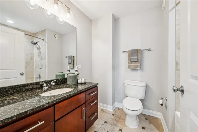 a bathroom with a granite countertop toilet sink and mirror