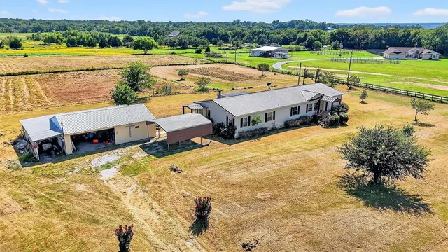 a view of a lake with lawn chairs and large trees