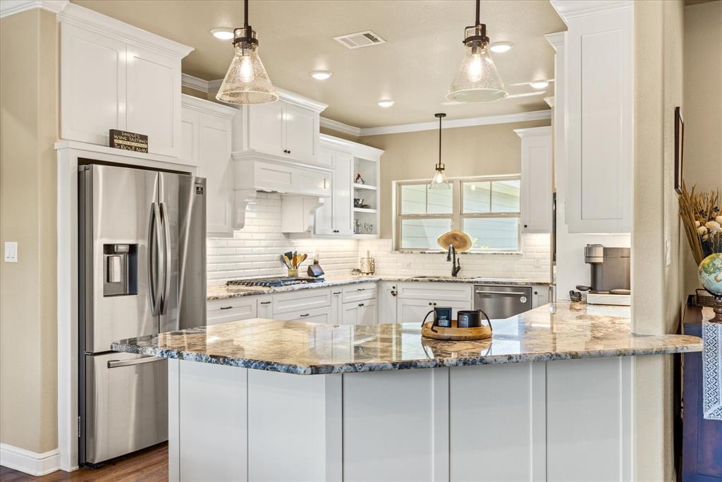 3868 Legend Trail Granbury, TX 76049 - Photo 14 of 39 Bright and cheery kitchen featuring Arctic White granite counters, decorative lighting, gas cooking, custom built-in spice and utensil pullouts.