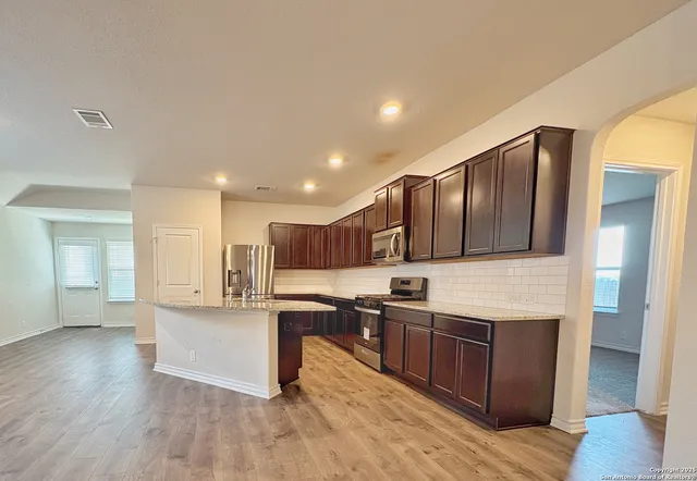a kitchen with stainless steel appliances kitchen island granite countertop a stove and a sink
