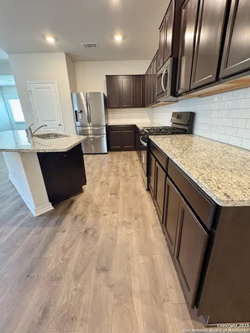 a large kitchen with stainless steel appliances kitchen island granite countertop a sink counter space and cabinets