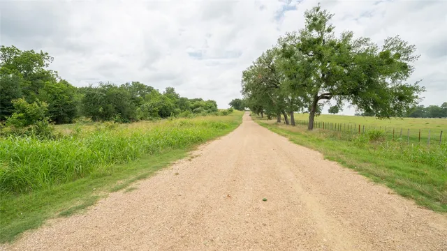 a view of a street with a yard and fence