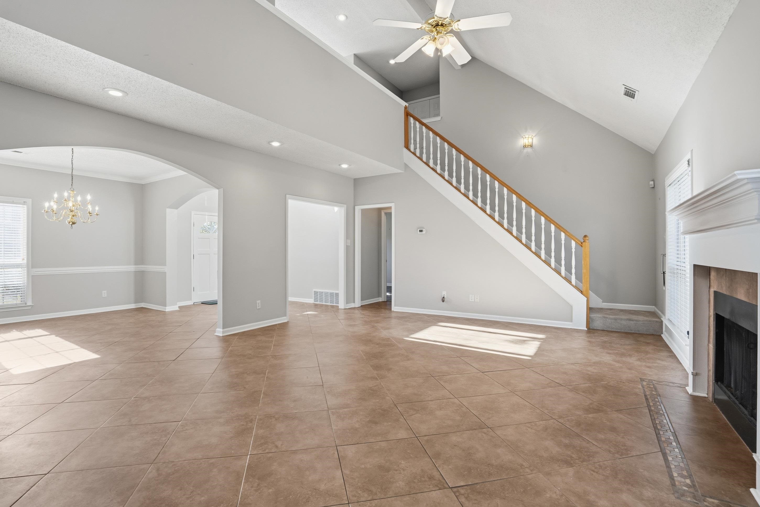 8570 May Orchard Lane Cordova, TN 38018 - Photo 4 of 35 Unfurnished living room with plenty of natural light, a fireplace with raised hearth, a chandelier, arched walkways, and high vaulted ceiling