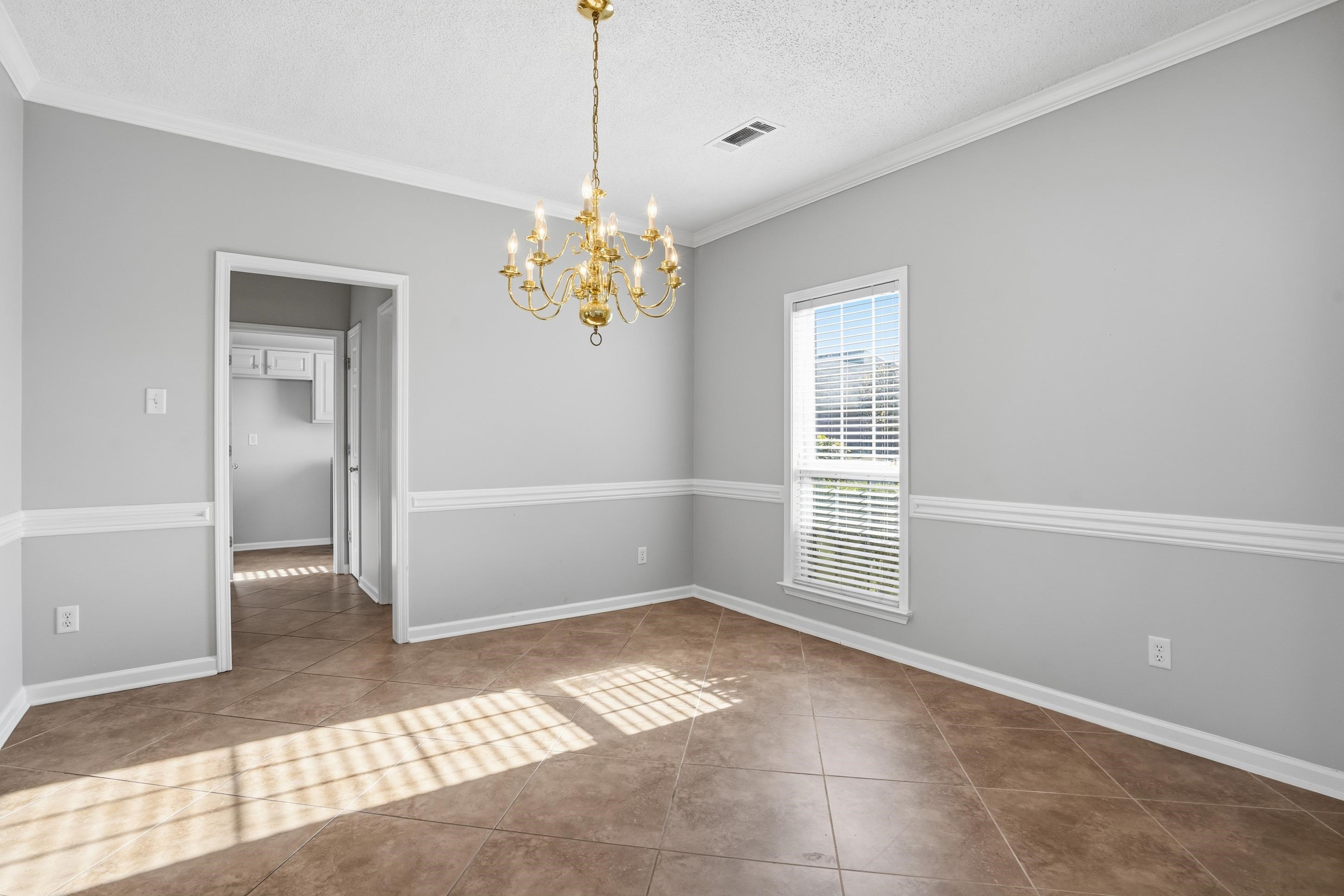 8570 May Orchard Lane Cordova, TN 38018 - Photo 6 of 35 Unfurnished room featuring a chandelier, a textured ceiling, crown molding, and tile patterned flooring