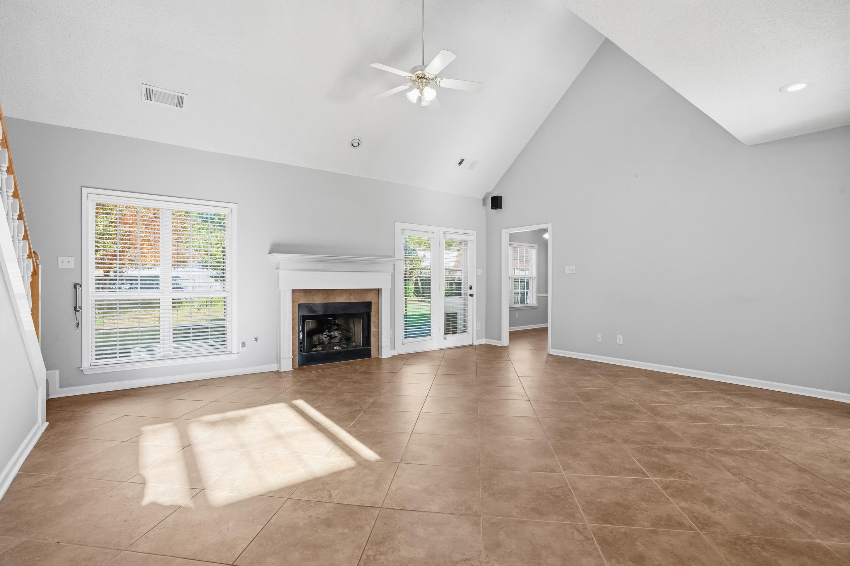 8570 May Orchard Lane Cordova, TN 38018 - Photo 7 of 35 Unfurnished living room featuring ceiling fan, high vaulted ceiling, a tile fireplace, and light tile patterned floors