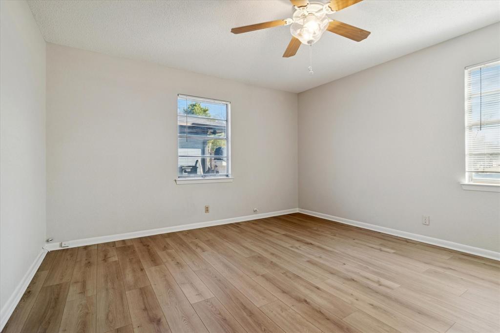 852 West Redbud Drive Hurst, TX 76053 - Photo 14 of 25 an empty room with wooden floor chandelier fan and windows