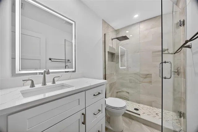 a bathroom with a double vanity sink toilet mirror and shower