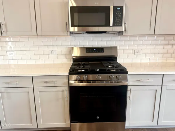 a kitchen with granite countertop white cabinets and black appliances