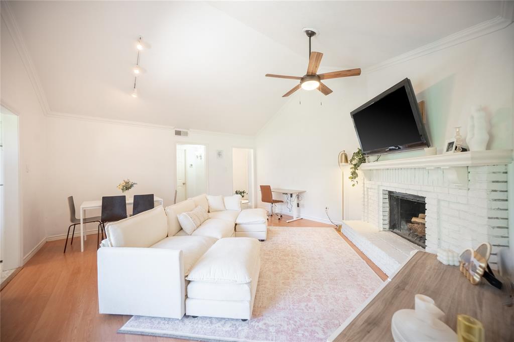 2835 Keller Springs Road, Unit 808 Carrollton, TX 75006 - Photo 7 of 16 Living area with wood finished floors, ceiling fan, baseboards, a brick fireplace, and visible vents
