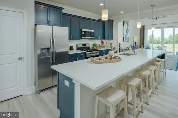 a kitchen with stainless steel appliances granite countertop a refrigerator a stove a sink a dining table and chairs