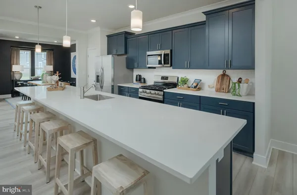 a kitchen with stainless steel appliances a sink a stove a refrigerator white cabinets and wooden floor