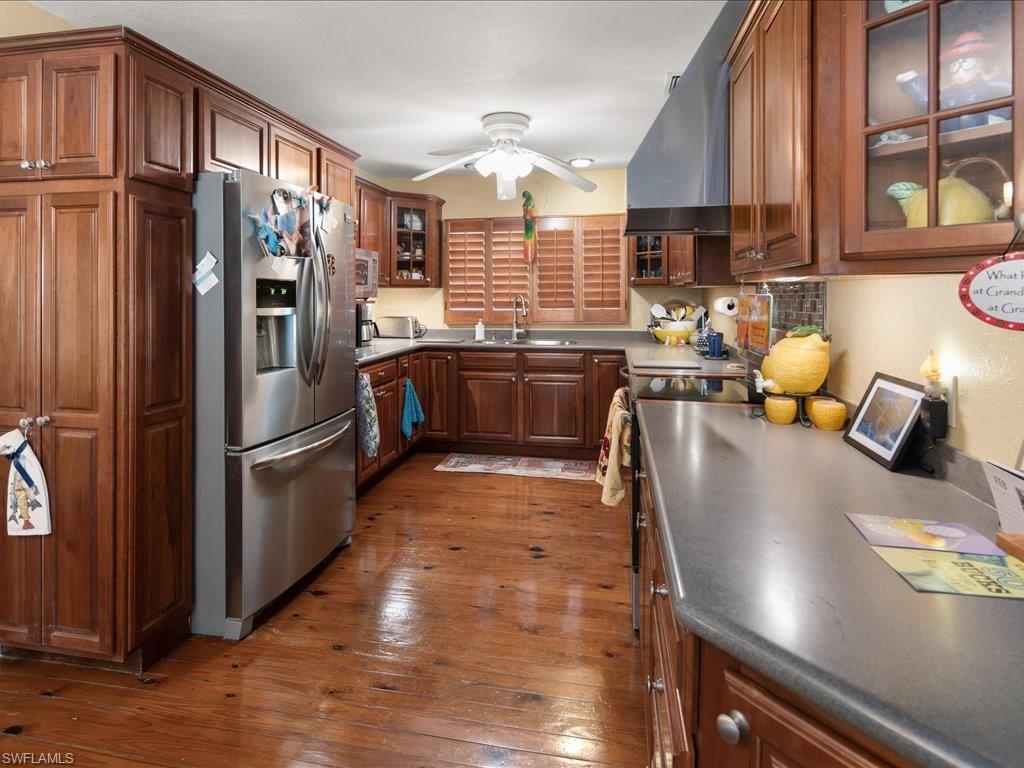 565 Coconut Avenue Goodland, FL 34140 - Photo 10 of 35 Kitchen with sink, exhaust hood, ceiling fan, stainless steel refrigerator with ice dispenser, and dark wood-type flooring