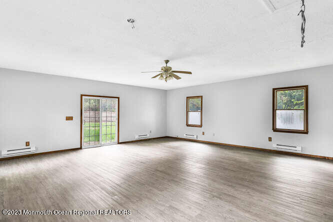 407 Cook Road Jackson, NJ 08527 - Photo 8 of 25 an empty room with wooden floor chandelier and windows