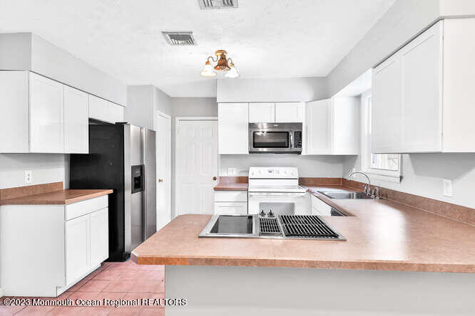 407 Cook Road Jackson, NJ 08527 - Photo 10 of 25 a kitchen with stainless steel appliances a stove a refrigerator a sink a stove with white cabinets
