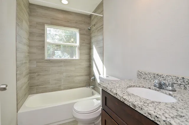 a bathroom with a granite countertop toilet a sink and bathtub