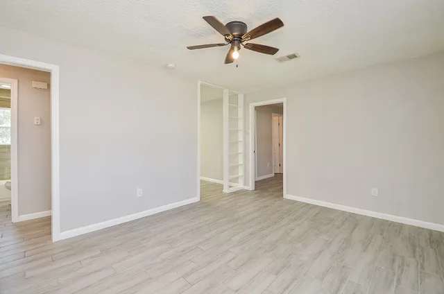 an empty room with wooden floor and ceiling fan