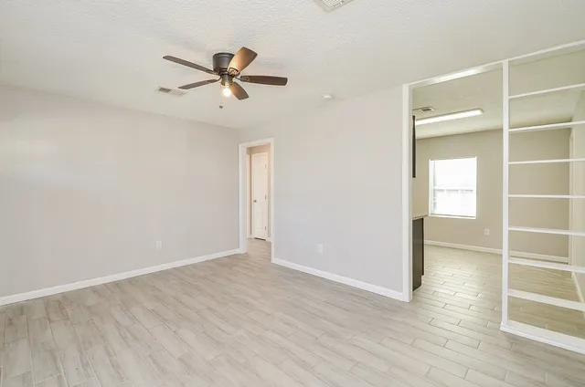 a view of an empty room with wooden floor and a window