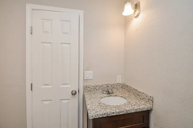 a bathroom with a granite countertop sink and vanity