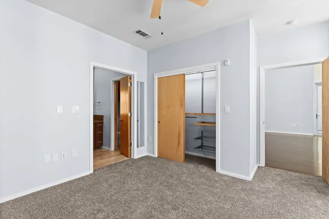 an empty room with closet and a chandelier fan