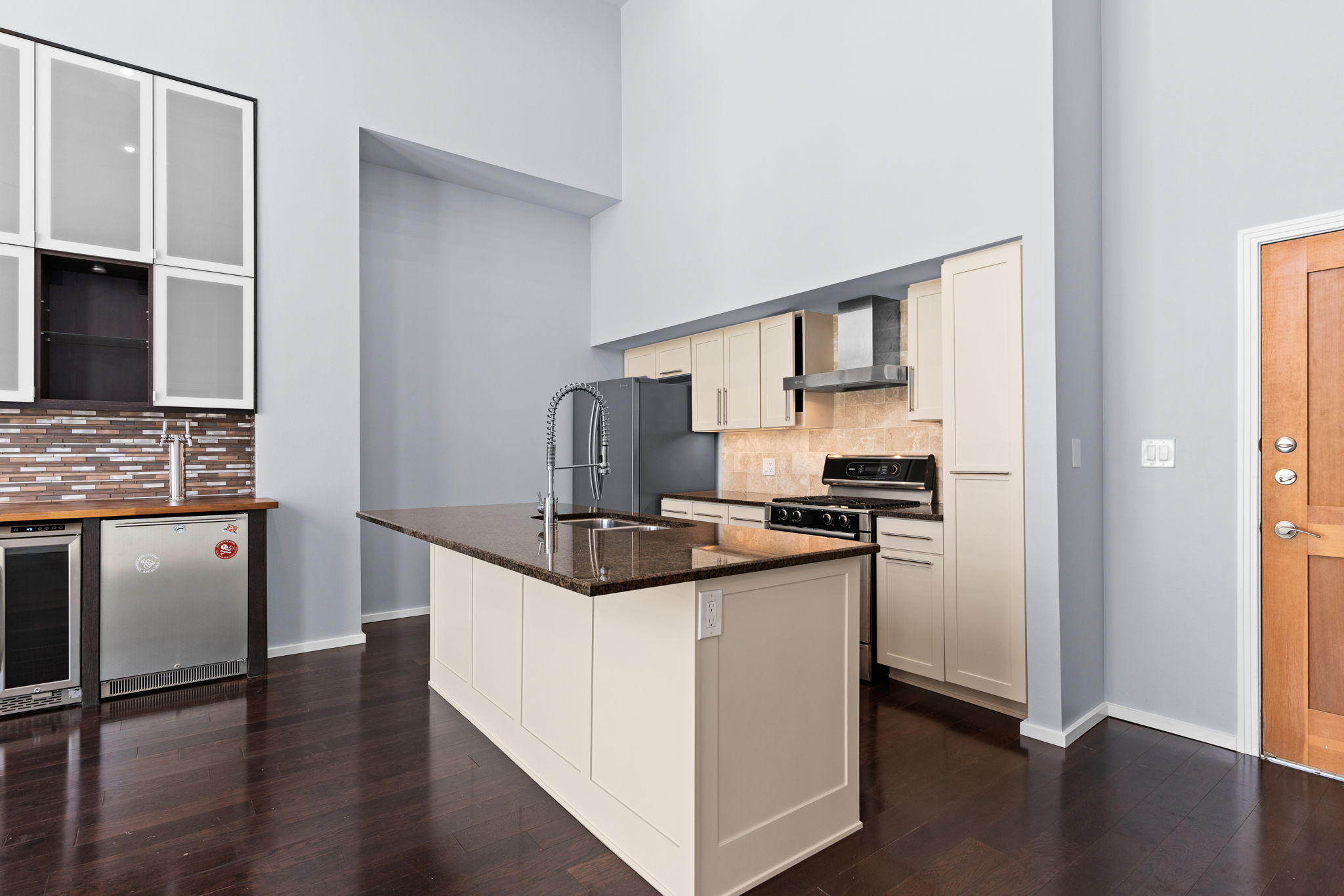 1600 Barton Springs Road, Unit 4602 Austin, TX 78704 - Photo 6 of 39 Kitchen featuring freestanding refrigerator, wall chimney exhaust hood, beverage cooler, tasteful backsplash, and a towering ceiling
