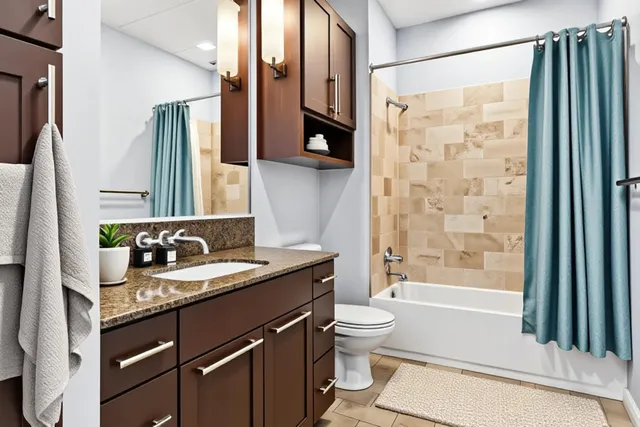 a bathroom with a granite countertop sink toilet and shower