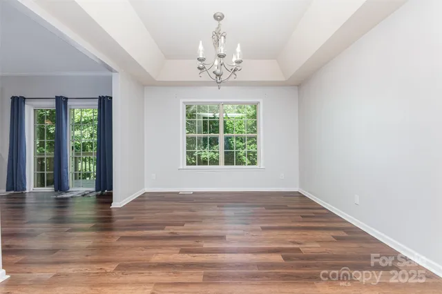 a view of an empty room with wooden floor and a chandelier