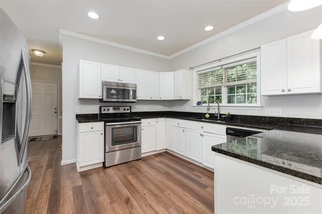 a kitchen with granite countertop a sink stainless steel appliances and window