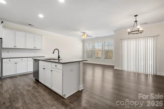 a kitchen with stainless steel appliances granite countertop a stove a sink and white cabinets with wooden floor