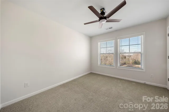 an empty room with windows and ceiling fan