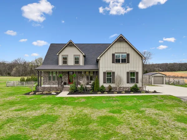 a front view of a house with garden and trees
