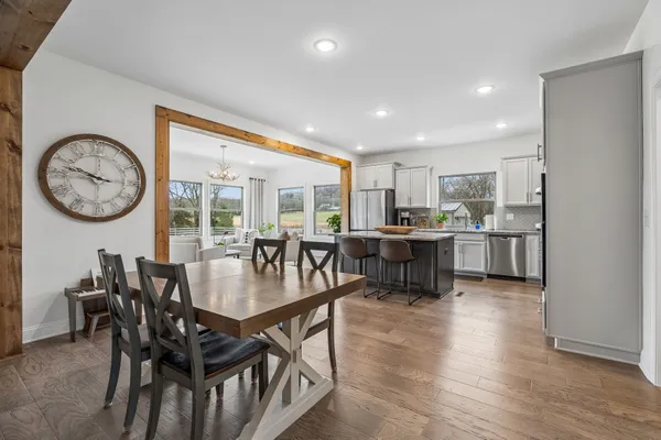 a kitchen with stainless steel appliances granite countertop a table chairs sink refrigerator and microwave