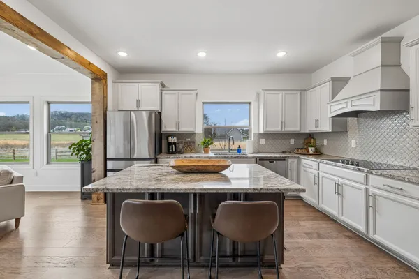 a kitchen with stainless steel appliances granite countertop a stove top oven a sink dishwasher a dining table and chairs with wooden floor