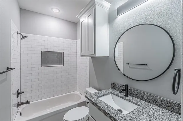 a bathroom with a granite countertop sink mirror toilet and bathtub