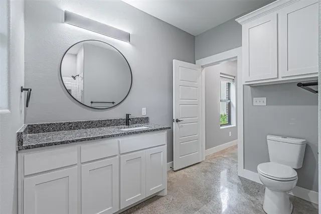 a bathroom with a granite countertop toilet sink and mirror