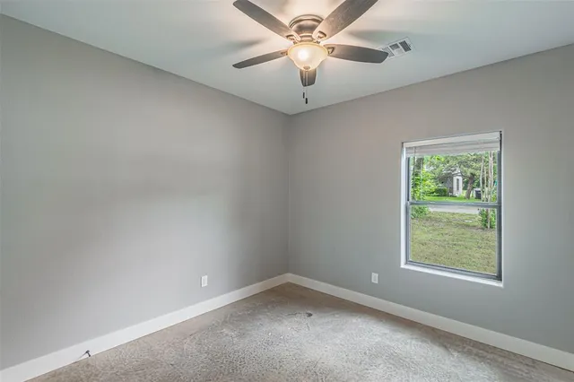 an empty room with a window and a fan