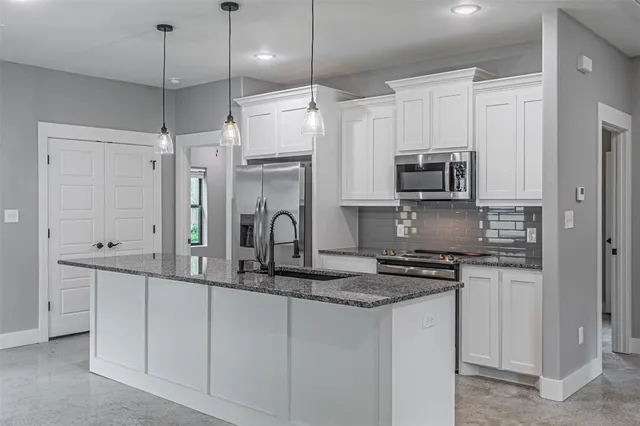 a kitchen with stainless steel appliances granite countertop a sink a stove a refrigerator a center island a stove and cabinets