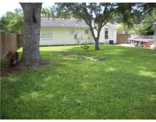 a house that is sitting in the grass with large trees