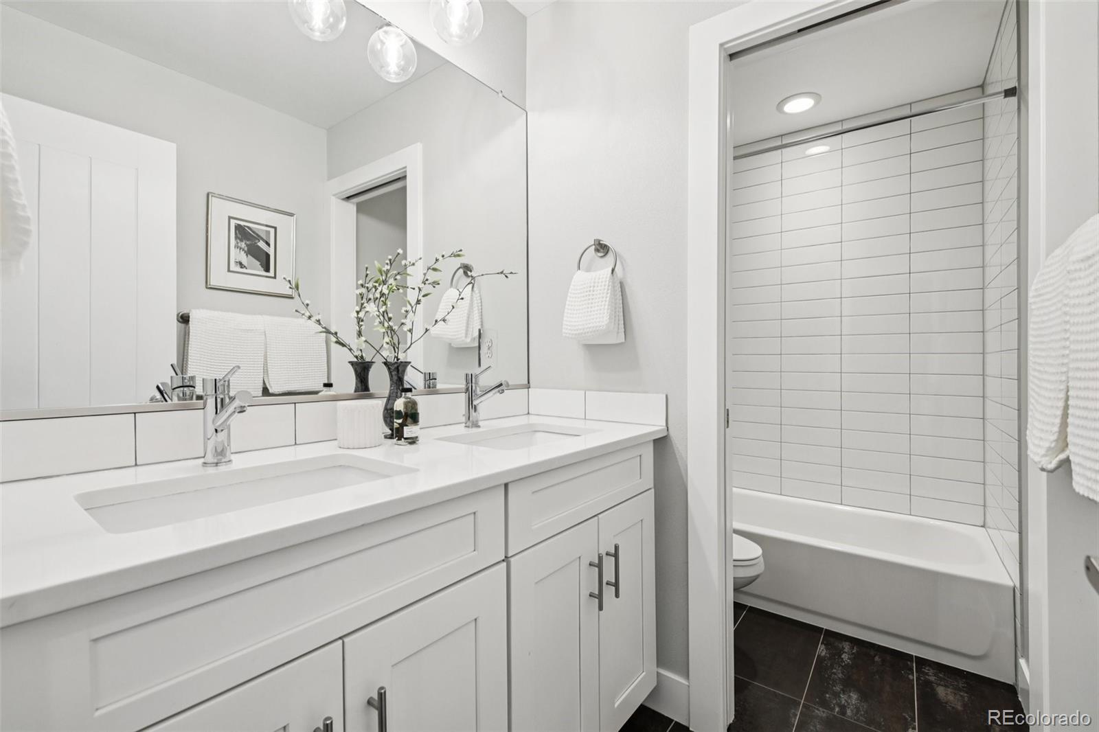 2825 Stout Street Denver, CO 80205 - Photo 24 of 42 a bathroom with a double vanity sink a shower and a mirror