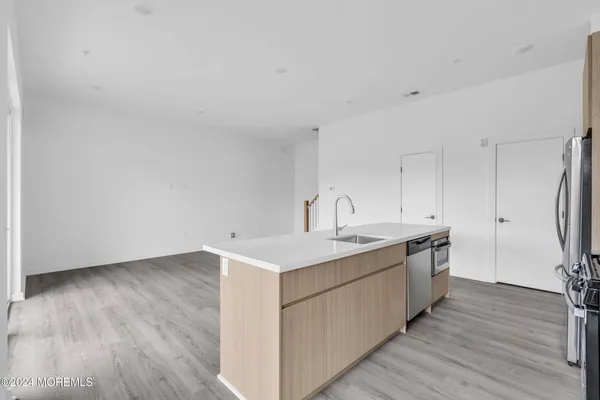a kitchen with a sink cabinets stainless steel appliances and wooden floor