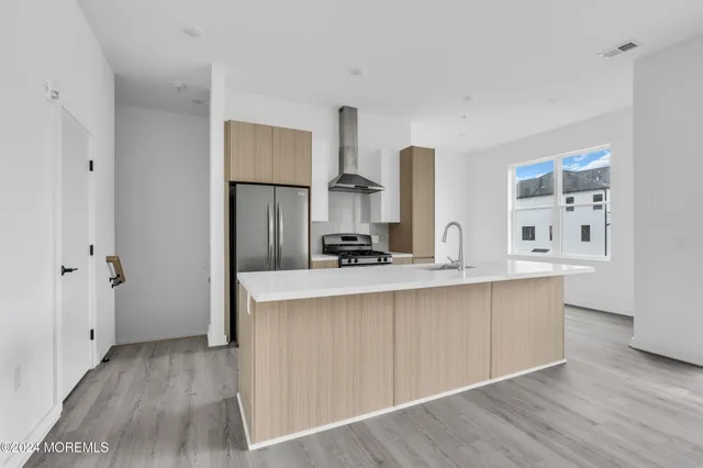a kitchen with stainless steel appliances a sink and wooden floor