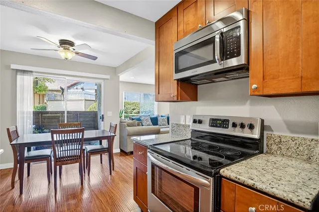 a kitchen with stainless steel appliances granite countertop a stove a microwave a dining table and chairs with wooden floor