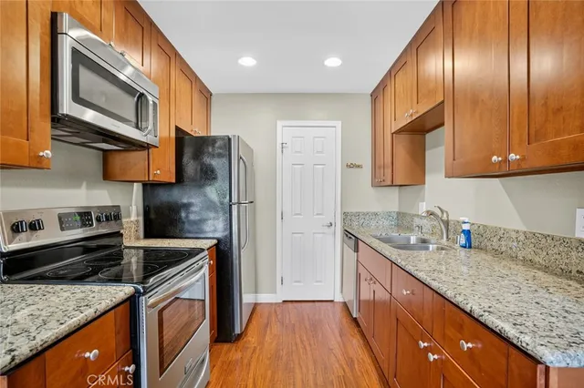 a kitchen with stainless steel appliances granite countertop a sink a stove and a wooden cabinets