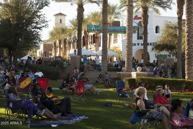 a group of people sitting in a yard in front of retail shops
