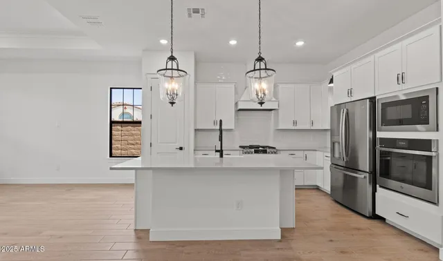 a kitchen with stainless steel appliances a refrigerator a sink and white cabinets