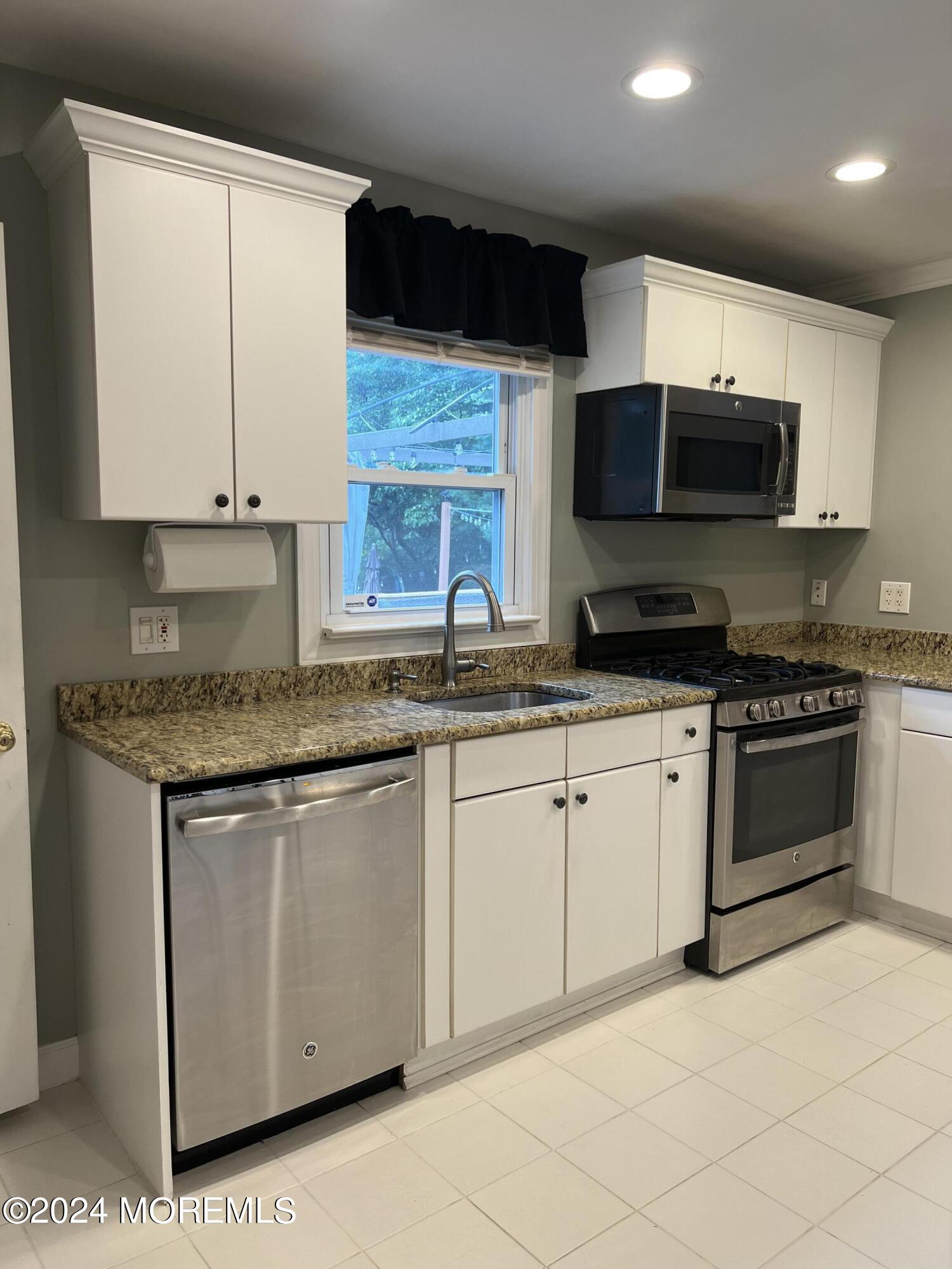 51 Lloyd Road Morganville, NJ 07751 - Photo 11 of 54 a kitchen with stainless steel appliances granite countertop a stove a sink and a microwave