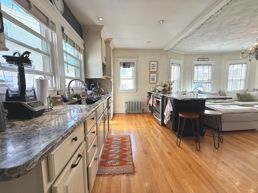 263 Powder House Boulevard, Unit 2 Somerville, MA 02144 - Photo 2 of 17 a large kitchen with kitchen island a large counter top space a sink a window and stainless steel appliances